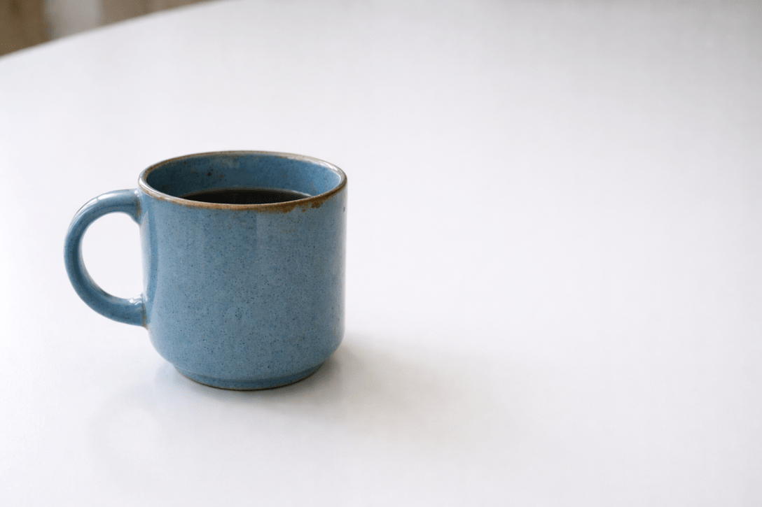 an abandoned blue coffee mug sits on the white table